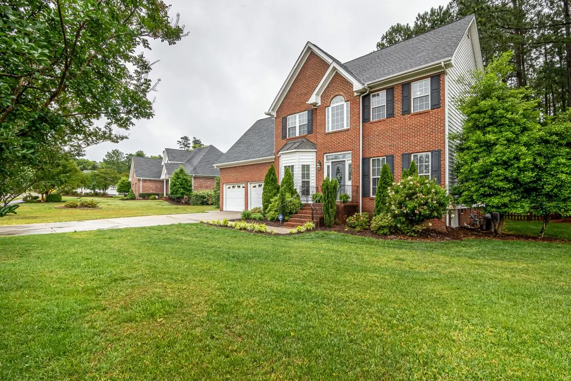 Brick residential house with a lawn and mature trees